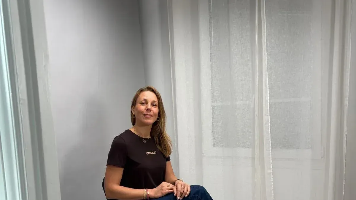 Femme souriante assise sur un plateau de tournage sur fond gris