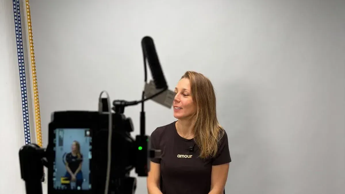 Coulisses du studio avec une femme assise devant la caméra et l'équipe technique
